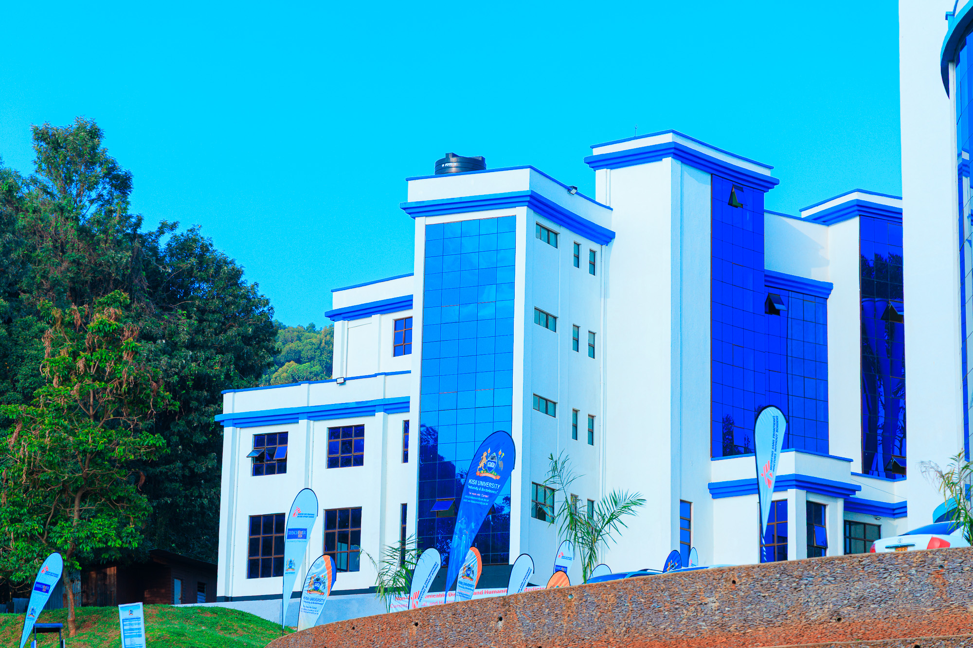 Block C at Kisii University, a modern blue glass teaching block lined with faculty banners
